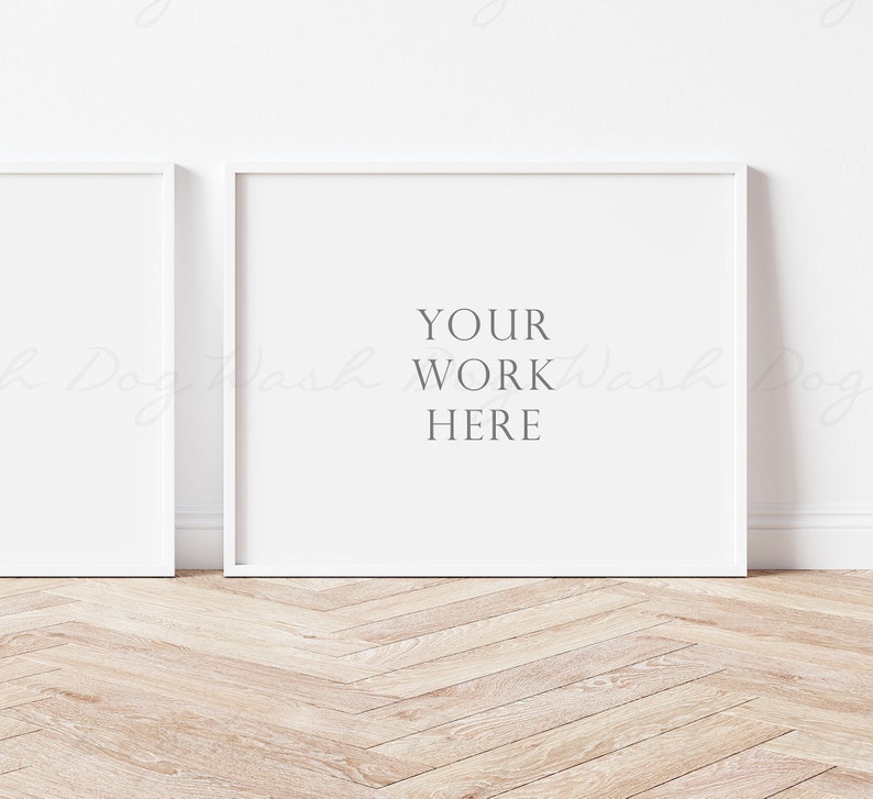 May include: Two white picture frames on a light wood floor. The frame on the right has the text "YOUR WORK HERE" in the center.