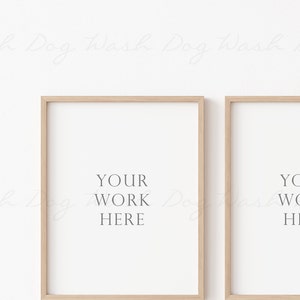 May include: Two light wood framed posters with white mats and the text "YOUR WORK HERE" centered on each poster.