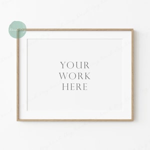 May include: A simple wooden frame with a white mat and the text "YOUR WORK HERE" in the center. The frame is hanging on a white wall.