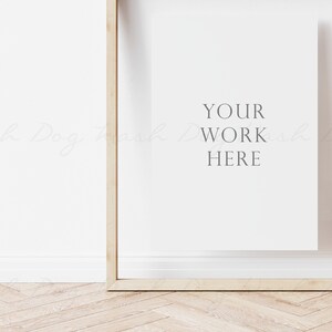 May include: A wooden frame with a white mat and the text "YOUR WORK HERE" in gray lettering. The frame is on a light wood floor.