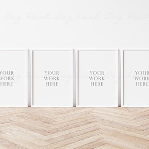 May include: Four white picture frames with a white mat and the text "YOUR WORK HERE" in each frame. The frames are hanging on a white wall above a light wood floor.