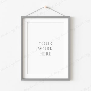 Puede incluir: Un marco de imagen gris con un paspartú blanco y un fondo blanco. El texto "YOUR WORK HERE" está impreso en el centro del marco.