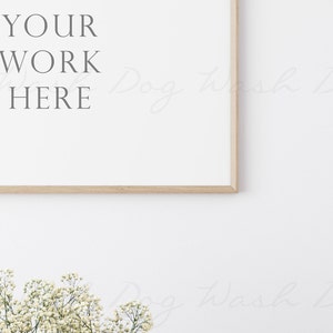 May include: A white frame with a wooden border, hanging on a white wall. The frame is empty and has the text "YOUR WORK HERE" written in grey text.