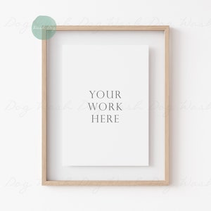 May include: A light wood frame with a white mat and a white paper insert with the text "YOUR WORK HERE" in the center.