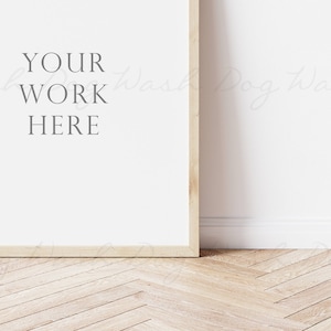 May include: A white framed poster with the text "YOUR WORK HERE" on a white wall with a wood floor.