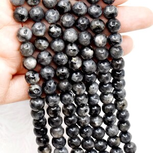 Puede incluir: Una hebra de cuentas de piedra preciosa de labradorita negra. Las cuentas son redondas y tienen un acabado liso y pulido. Las cuentas están enhebradas en un cordón elástico transparente.