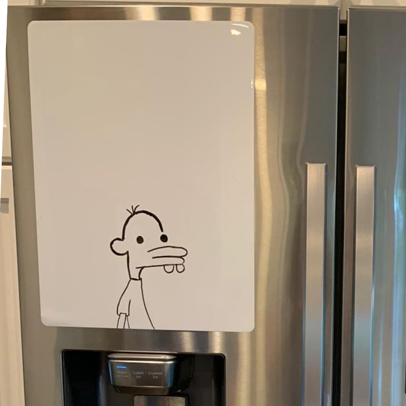 Puede incluir: Un refrigerador blanco con una pizarra blanca de borrado en seco en la puerta. La pizarra tiene un dibujo en blanco y negro de un personaje de dibujos animados con una nariz grande y una boca ancha.