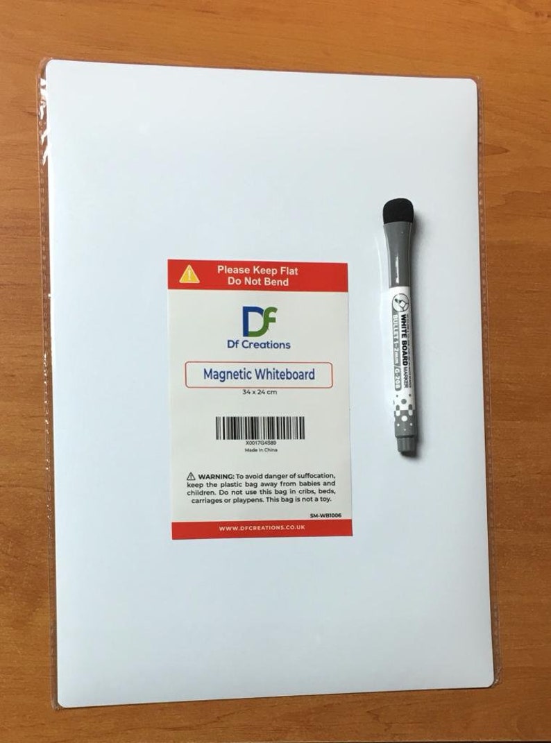 May include: A white magnetic whiteboard with a red and white label that says "Please Keep Flat Do Not Bend" and "Df Creations Magnetic Whiteboard 34 x 24 cm". The label also includes a barcode and the text "Made in China". A warning label is below the barcode. A white dry erase marker with a black cap is on the right side of the image.