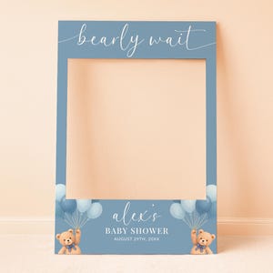 May include: A blue photo booth prop with the text "bearly wait" in white script. The bottom of the prop has the text "alex's BABY SHOWER AUGUST 29TH, 20XX". It features illustrations of teddy bears and balloons.