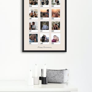 May include: A framed wall art print featuring a grid of twelve square photographs, each labeled with a month from March to February. The print includes the text Happy Anniversary at the bottom, set against a light beige background with a black frame.