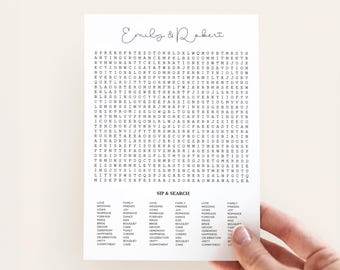 May include: A white rectangular card featuring a word search puzzle with the names Emily & Robert at the top in script font. Below the grid, the text SIP & SEARCH appears above columns of words including love, wedding, vows, and marriage.