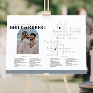 May include: A white wedding sign featuring the text How well do you know EMILY & ROBERT, a photograph of a couple in an arch frame, and a crossword puzzle with numbered clues for Across and Down categories printed in black ink.