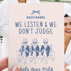May include: A greeting card with the text "Bach Babes We Listen & We Don't Judge" and "Girls Gone Mild Edition". The card features a blue illustration of three women on a couch, holding champagne glasses.