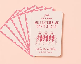 Peut inclure: Un jeu de cartes rectangulaires aux bords arrondis et festonnés. La carte du dessus présente une icône de nœud rose, le texte BACH BABES, WE LISTEN & WE DON'T JUDGE, et une illustration de trois personnes en peignoir tenant des verres, avec Girls Gone Mild EDITION en bas.