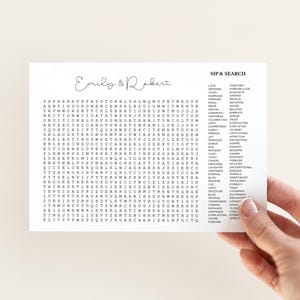 May include: A white rectangular card featuring a word search puzzle titled SIP & SEARCH with the names Emily & Robert in script at the top. The grid contains various letters and a list of wedding-themed words in black ink.