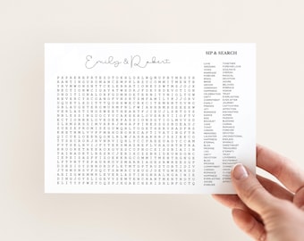 Op de afbeelding: Een witte rechthoekige kaart met een woordzoeker getiteld SIP & SEARCH met de namen Emily & Robert in cursief schrift bovenaan. Het raster bevat diverse letters en een lijst met woorden in het thema van een bruiloft.