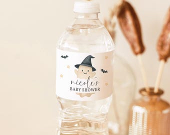 Könnte beinhalten: Eine durchsichtige Plastikwasserflasche mit einem weißen Etikett, das einen Cartoon-Geist mit schwarzem Hexenhut, kleine schwarze Fledermäuse und goldene Sterne zeigt. Der Text auf dem Etikett lautet "nicole's BABY SHOWER".