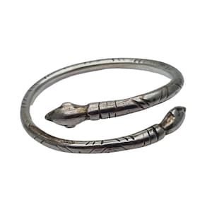 May include: Silver snake bracelet with a detailed design. The bracelet is coiled and has a snake head at each end.