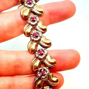 Può includere: Un braccialetto in oro e argento con un design floreale e pietre preziose rosa.