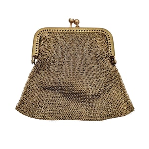 May include: Antique gold-toned metal mesh purse with a kiss-lock clasp. The purse features a delicate chainmail design, with a rectangular frame and a rounded bottom. The clasp has a decorative, ornate design.