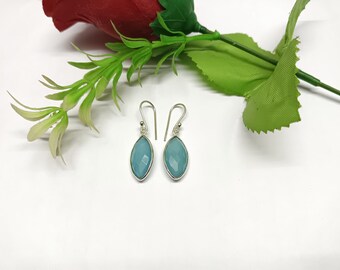 May include: A pair of silver dangle earrings with light blue gemstone drops. The earrings have a simple design and are perfect for everyday wear.