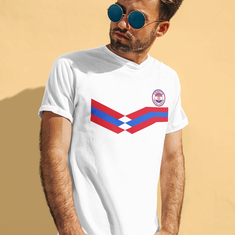 May include: White t-shirt with a red, blue, and white chevron design and a circular logo with the text "Croatia" and a checkered pattern.