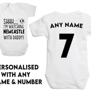 Peut inclure: Combinaison b&eacute;b&eacute; blanche avec texte noir qui dit "SHHH... I'M WATCHING NEWCASTLE WITH DADDY!" et un graphique de ballon de football noir. Combinaison b&eacute;b&eacute; blanche avec texte noir qui dit "ANY NAME" et le num&eacute;ro "7".