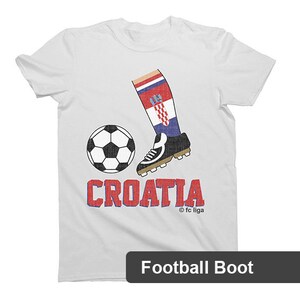 May include: White t-shirt with a red, white, and blue soccer boot kicking a soccer ball. The text "CROATIA" is printed in red and blue letters below the boot. The text "&copy; fc liga" is printed in small letters below the text "CROATIA".