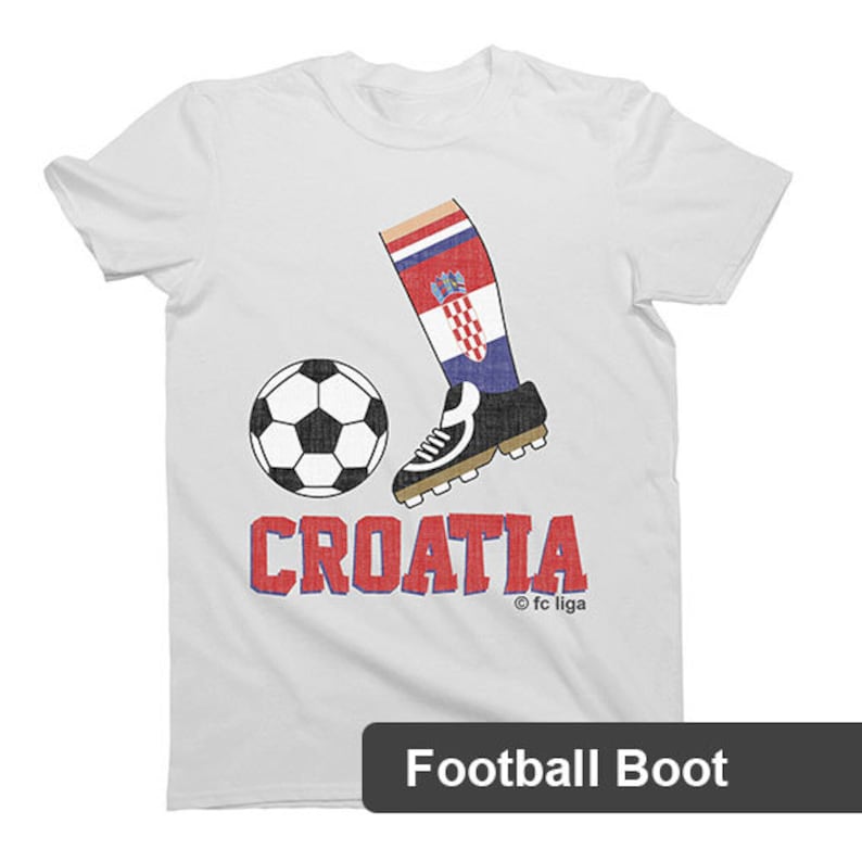 May include: White t-shirt with a red, white, and blue soccer boot kicking a soccer ball. The text "CROATIA" is printed in red and blue letters below the boot. The text "&copy; fc liga" is printed in small letters below the text "CROATIA".