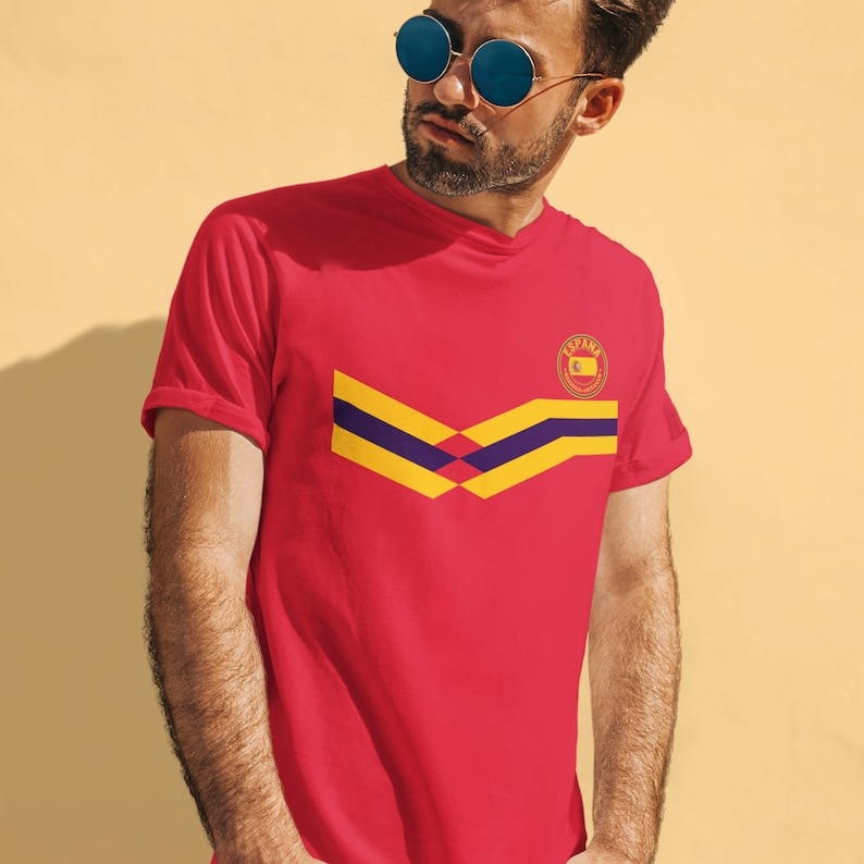 May include: Red t-shirt with a yellow and purple chevron design and a small circular logo with the word "ESPA&Ntilde;A" in it.