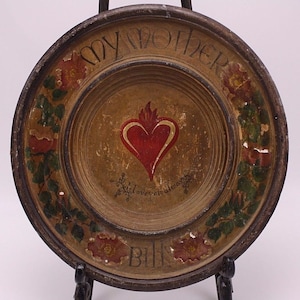 May include: A wooden plate with a painted heart and floral design. The plate has the words "My Mother" and "Bill" written on it.