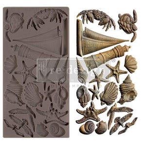 Könnte beinhalten: Eine Silikonform mit verschiedenen nautischen Motiven. Die Form enthält detaillierte Formen von Muscheln, Seesternen, einem Leuchtturm, einem Segelboot, einer Krabbe, einer Schildkröte und Möwen. Die Form ist dunkelgrau.