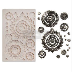 May include: A silicone mold with 17 different designs of ornate, circular, and star-shaped patterns. The mold is white and the designs are raised. There are also 17 silver-colored metal ornaments that match the designs in the mold.