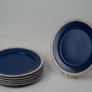 Könnte beinhalten: Ein Stapel von sechs blauen und weißen Keramik-Dinnertellern. Die Teller haben einen weißen Rand und eine blaue Mitte.