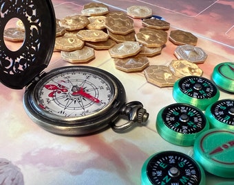 May include: A vintage-style compass with a detailed face and red needle, next to several green and black compass tokens and tan game pieces. The compass is open, revealing its intricate design. The items are on a game board.