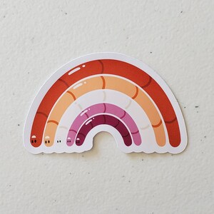 May include: A rainbow-coloured sticker with a design of a rainbow made of worms. The rainbow is in the colours of the lesbian pride flag: red, orange, yellow, pink, purple, and red.