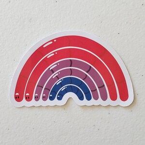 May include: A rainbow sticker with red, purple and blue stripes. The rainbow is made up of worm-like shapes with eyes.