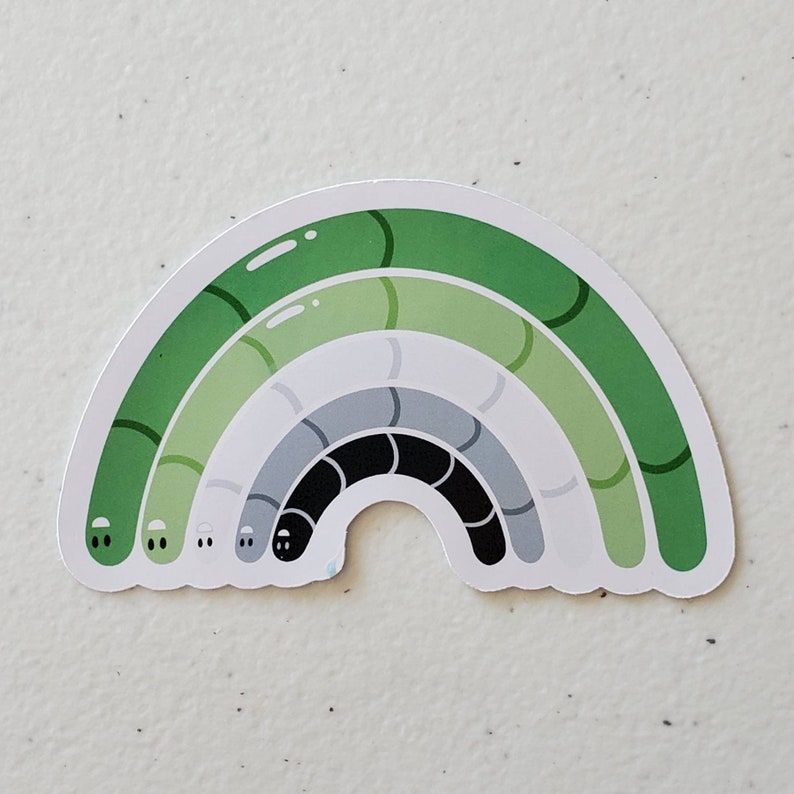 May include: A green, grey, and black rainbow sticker with a worm design. The sticker is shaped like a rainbow with a worm-like design in each colour band.