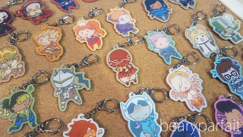 May include: A collection of colorful Overwatch character keychains featuring various characters from the game. The keychains are made of a durable material and feature detailed artwork of each character.