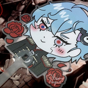 May include: A clear plastic fan featuring a cartoon character with blue hair and red eyes. The character is wearing a dark green uniform with gold accents. Red roses and the text "Beany Parfait" are also visible.