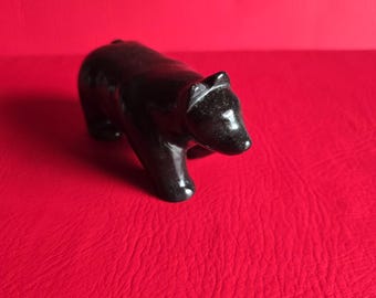 May include: A black, carved bear figurine. The bear is standing on all fours and has a simple, stylized design.