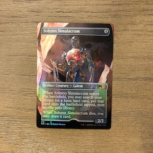 May include: A Magic: The Gathering card featuring Solemn Simulacrum, a 4-mana artifact creature with a 2/2 power and toughness. The card has a metallic blue and red golem with a red heart on its chest. The card text reads "When Solemn Simulacrum enters the battlefield, you may search your library for a basic land card, put that card onto the battlefield tapped, then shuffle your library. When Solemn Simulacrum dies, you may draw a card."