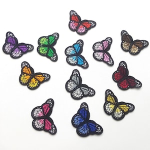 May include: A collection of embroidered butterfly patches in various colors, including purple, green, orange, blue, pink, red, yellow, and brown. Each patch features a black border and detailed wing patterns.