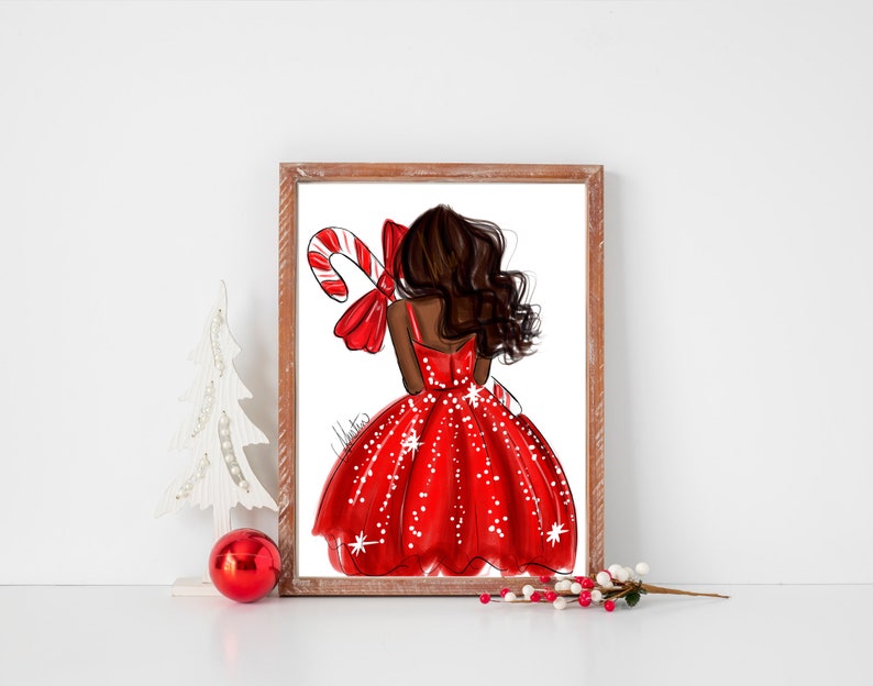 Op de afbeelding: Een ingelijste illustratie van een persoon in een rode jurk met witte stippen, met een zuurstok. Het kunstwerk heeft een kerstthema, met een rode strik en een witte kerstboomversiering op de voorgrond.