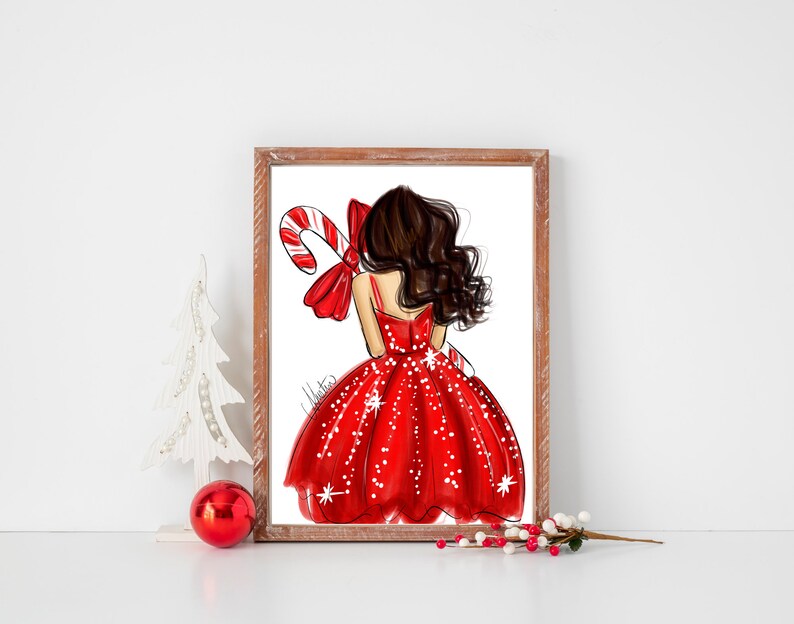 Op de afbeelding: Een ingelijste illustratie van een vrouw in een rode jurk met witte stippen, met een zuurstok en strik. Het kunstwerk heeft een kerstthema, met een witte kerstboom en rode bal op de voorgrond.