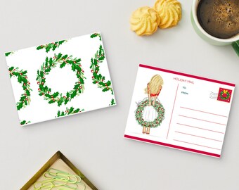Puede incluir: Dos postales y una taza de café sobre una superficie gris claro. Una postal presenta un patrón repetido de coronas de acebo verdes con bayas rojas. La otra postal tiene un borde rojo y una ilustración de una mujer sosteniendo una corona.