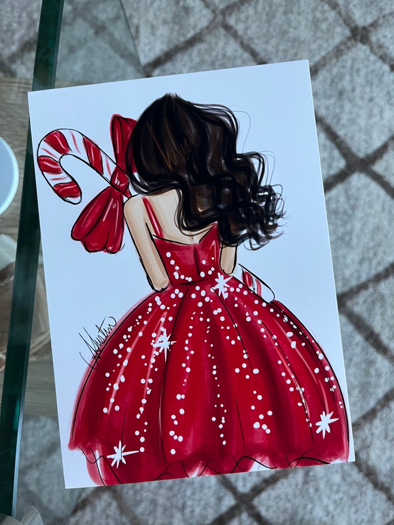 Op de afbeelding: Illustratie van een vrouw in een rode jurk met witte stippen en steraccenten, die een zuurstok vasthoudt. Het kunstwerk toont donker haar en een grote rode strik. De handtekening van de kunstenaar is zichtbaar.