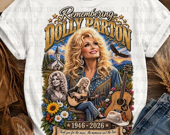 May include: A white t-shirt featuring a graphic of Dolly Parton with the text Remembering Dolly Parton 1946-2026. The design includes a portrait of Dolly, a smaller image of her playing guitar, a church, a flying eagle, sunflowers, and a cowboy hat.