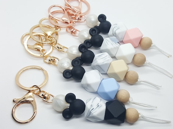 Disney family silicone beaded keychains. Features mouse ears and a gray marbled bead with a choice of black, beige, blue, white, or pink. Disney family silicone beaded keychains. Features mouse ears and a gray marbled bead with a choice of black, beige, blue, white, or pink.