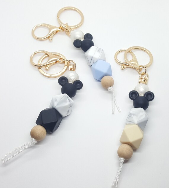 Disney family silicone beaded keychains. Features mouse ears and a gray marbled bead with a choice of black, beige, blue, white, or pink. Disney family silicone beaded keychains. Features mouse ears and a gray marbled bead with a choice of black, beige, blue, white, or pink.